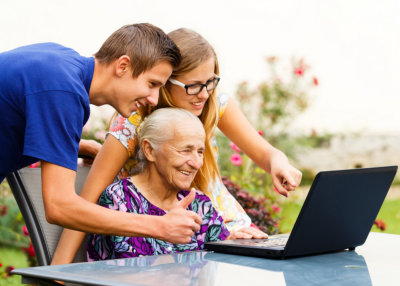 elderly woman and her grandchildren looking on the laptop