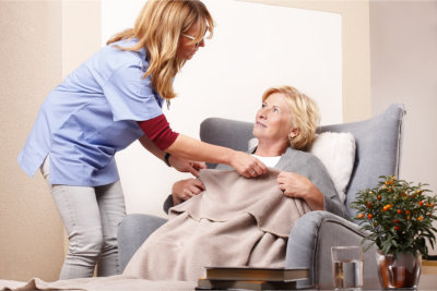 caregiver assiting on blanket to elderly woman