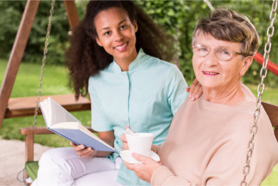 caregiver reading a book with elderly woman